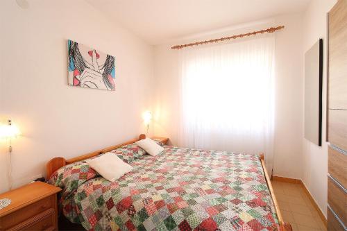 a bedroom with a bed with a quilt and a window at Apartments with parking space Premantura, Medulin - 20752 in Pula
