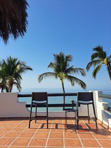 布塞里亞斯的住宿－Villa Cobojo，棕榈树阳台的两把椅子和一张桌子