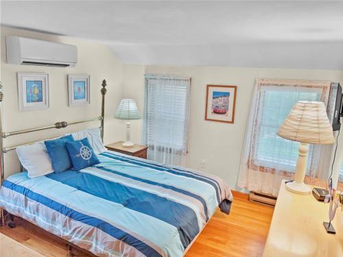 1 dormitorio con 1 cama con sábanas azules y 2 ventanas en 180 Hardings Beach Road Chatham Cape Cod - The Cape Escape, en Chatham