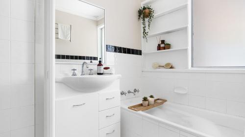 a white bathroom with a sink and a mirror at The Nook in Bowral