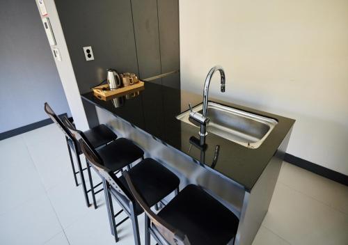 uma cozinha com um lavatório e algumas cadeiras em YJ Hotel em Gapyeong