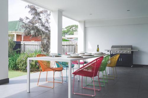 uma cozinha com uma mesa com cadeiras coloridas em La Via Del Mare - SUNDAY FOR FREE em Dromana