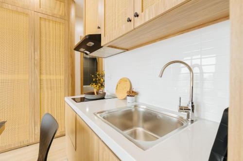 a kitchen with a stainless steel sink and wooden cabinets at Myrcella Urban Studio in Hanoi