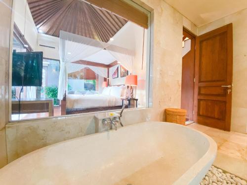a large bath tub in a room with a bedroom at Alea Villa by Premier Hospitality Asia in Jimbaran