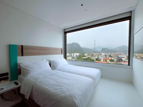 1 dormitorio con 2 camas y ventana grande en SOJO Hotel Hoa Binh en Hòa Bình