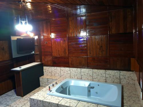y baño con bañera y paredes de madera. en Motel Scorpios, en Lages