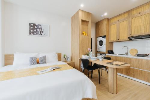 a bedroom with a bed and a table and a kitchen at Myrcella Urban Studio in Hanoi