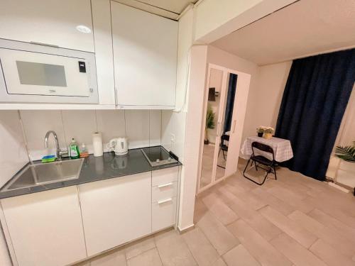 - une cuisine avec des placards blancs, un évier et une table dans l'établissement City Center Apartment, à Zurich