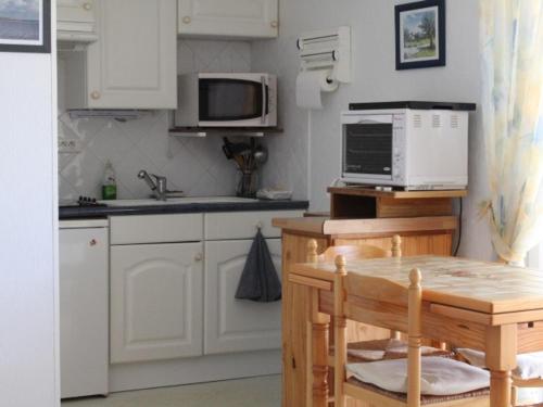 une cuisine avec des armoires blanches et une table avec un micro-ondes dans l'établissement Appartement tout confort proche plage avec parking privé - FR-1-482-8, à Fort-Mahon-Plage
