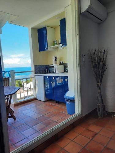 une cuisine avec des placards bleus et une vue sur l'océan dans l'établissement Martinique La Trinité KAZAKASSY Studio plain-pied, fonctionnel et vue mer, à La Trinité