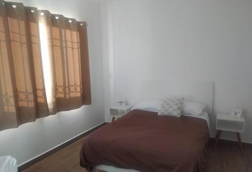 a bedroom with a bed and two windows at Dpto en el centro con estacionamiento. in Aguascalientes