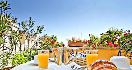 una mesa con zumo de naranja y pan en el balcón en Hotel Cinquantatre, en Roma
