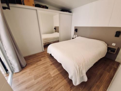 een slaapkamer met een wit bed in een kamer bij Cosy ecolodge with shared heated pool 10 from the beach in Les Mathes