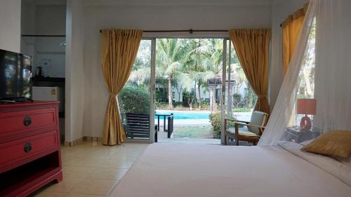 a bedroom with a bed and a door to a pool at Kalamona Seaview in Prachuap Khiri Khan