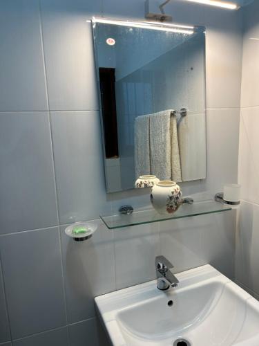uma casa de banho branca com um lavatório e um espelho em City Stay By Sunrise em Colombo
