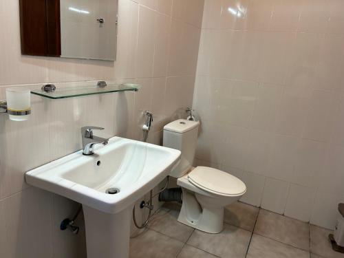 a white bathroom with a toilet and a sink at City Stay By Sunrise in Colombo