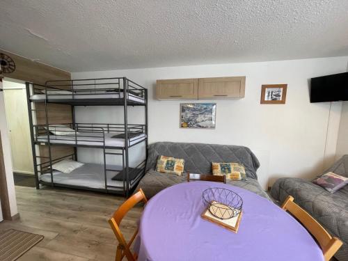 - un salon avec une table violette et des lits superposés dans l'établissement Studio rénové avec accès direct aux pistes, bien équipé - FR-1-165A-169, à Enchastrayes