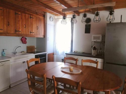 une cuisine avec une table en bois avec des chaises et un réfrigérateur dans l'établissement Appartement confortable et bien équipé, idéalement situé au centre de Pra-Loup avec terrasse orienté sud-est - FR-1-165A-158, à Uvernet