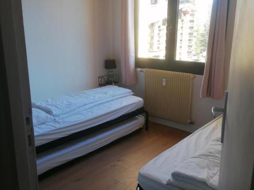 une chambre avec deux lits et deux fenêtres dans l'établissement Appartement confortable et bien équipé, idéalement situé au centre de Pra-Loup avec terrasse orienté sud-est - FR-1-165A-158, à Uvernet
