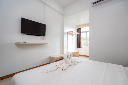 a white bedroom with a bed with a tv on the wall at TOP INN โรงแรมท็อปอินน์ in Maha Sarakham