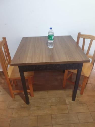 a wooden table with two chairs and a bottle on it at Wall Apartamentos in Hohenau