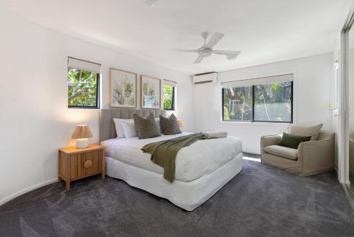 a white bedroom with a bed and a chair at 1 Horizon Terraces Beautifully Styled Duplex Perfect Beach Vibes in Sunshine Beach