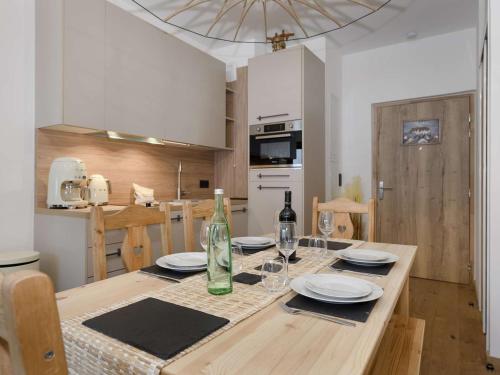 - une table à manger avec des assiettes et des bouteilles de vin dans l'établissement Appartement neuf skis aux pieds, 4 pers, Courchevel Moriond, balcon, parking, wifi - FR-1-631-131, à Courchevel