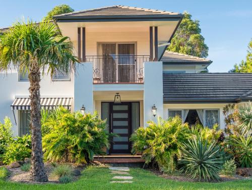 a house with a palm tree in front of it at Byron Studio Apartment in Suffolk Park