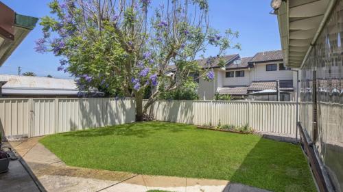 a backyard with a fence and a tree at Mara Bello - Umina Beach in Umina