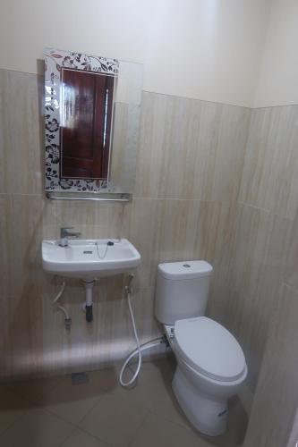 a bathroom with a white toilet and a sink at Berlian Hotel in Ende