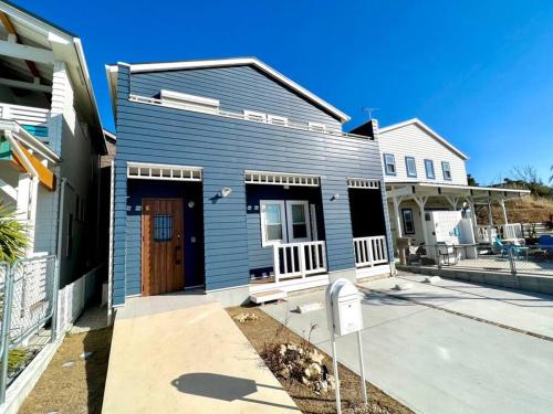 a blue house with a brown door on a street at studio Symphonia x Fukutsu in Fukuma