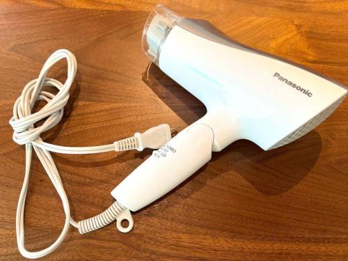 a white electric hair dryer on a wooden table at studio Symphonia x Fukutsu in Fukuma