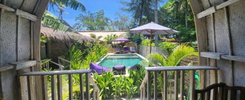 - une piscine avec 2 chaises et un parasol dans l'établissement Purple Beach - Maïthélia - Gili Air, à Gili Air