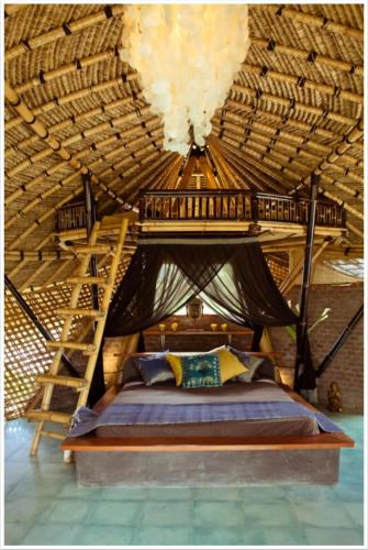 a bedroom with a bed in a straw ceiling at Firefly Eco Lodge in Ubud