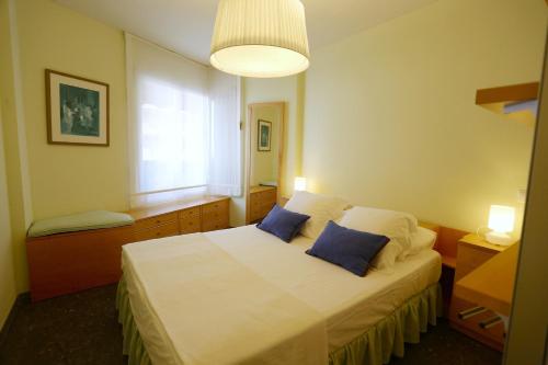 a bedroom with a bed with two blue pillows at Apartamentos Alquihouse Vilafortuny in Cambrils