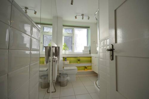 La salle de bains blanche est pourvue de toilettes et d'une fenêtre. dans l'établissement Flat in the heart of Camden Town, à Londres
