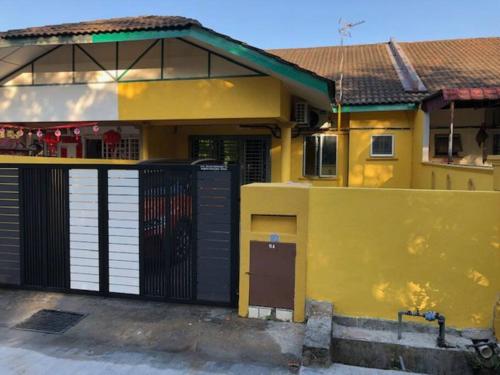 a yellow house with a gate in front of it at irdahusna homestay 