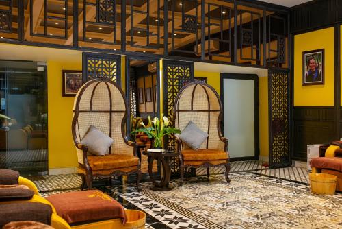 a lobby with two chairs and a table and yellow walls at Eden Central Hotel & Spa in Sa Pa