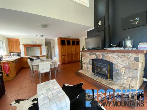 a living room with a stone fireplace and a table at Inala 3 in Thredbo