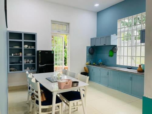 une cuisine avec des armoires bleues, une table et des chaises dans l'établissement Mon House, à Bảo Lộc