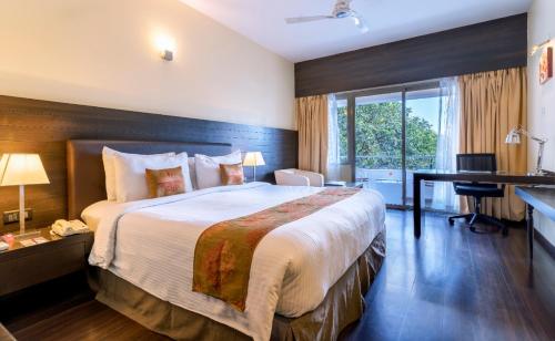 Habitación de hotel con cama grande y escritorio. en THE WOODROSE, en Bangalore