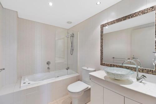 a bathroom with a sink and a tub and a toilet at Sandy Cove Apartment The Entrance 29 in The Entrance