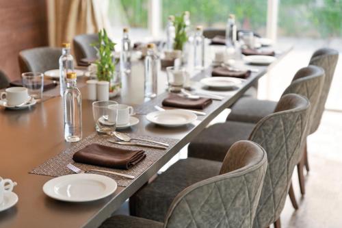 a long table with chairs and plates and napkins at Ramada by Wyndham Aligarh GT Road in Alīgarh