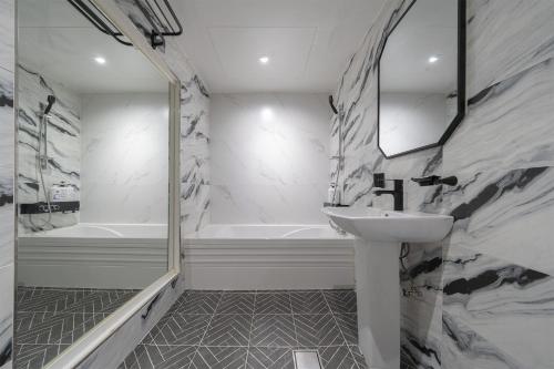 BY THS Curve Hotel Ikusan في Iksan: حمام مع حوض وحوض استحمام