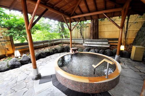 a hot tub in a pavilion with a bench at Aura Tachibana in Hakone