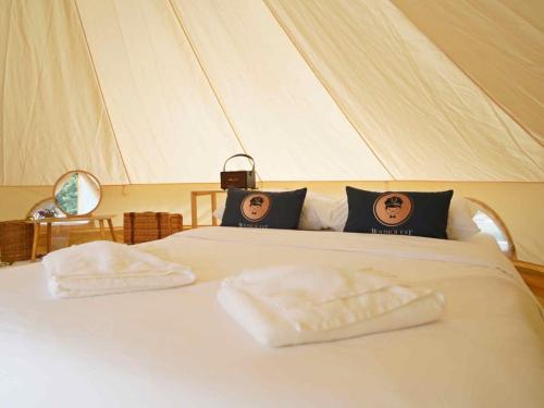 a bed in a tent with two towels on it at Yellowstone Camps Resort Khao Yai in Pak Chong