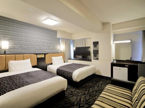 Cette chambre comprend deux lits et une télévision. dans l'établissement APA Hotel Kumamoto Sakuramachi Bus Terminal Minami, à Kumamoto