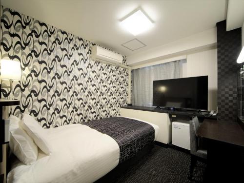 a hotel room with a bed and a flat screen tv at APA Hotel Kumamoto Sakuramachi Bus Terminal Minami in Kumamoto