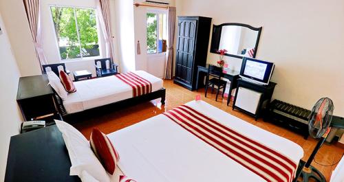 a bedroom with two beds and a desk with a television at Lam Bao Long Hotel in Hue
