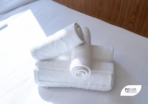 a stack of white towels sitting on a bed at Luke Stays - Dunya Tower in Dubai
